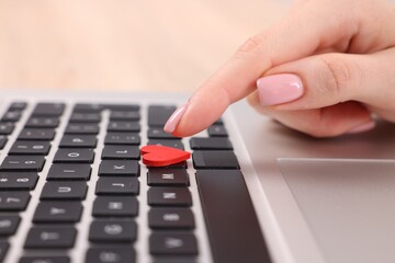 Online dating site. Woman touching red heart on laptop at table, closeup