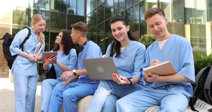 Group of medical students in uniforms studying together near building outdoors