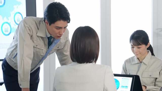 大画面モニターの前でミーティングする作業員のグループ