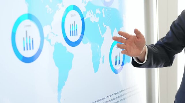 A male business person explaining something using a world map on a large screen monitor