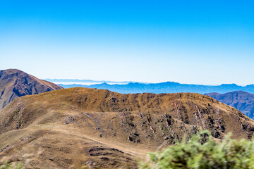 Panoramic vista of rolling arid mountains fading into the horizon, under a bright blue sky, Salta