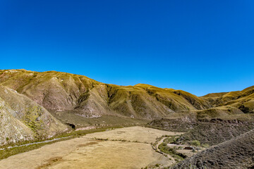 Panoramic view of a green valley with small farms and houses amidst the rugged Andean landscape of Salta.