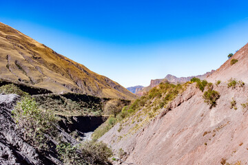 Stunning geological gorge featuring a dry creek and textured, colorful mountain sides in the Andes.