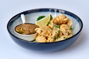 A Delicious Plate of Crispy Fried Delicacies Accompanied by Tangy Dipping Sauces and Fresh Lime for an Exquisite Culinary Experience