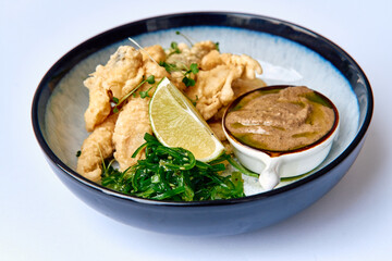 Deliciously Crispy Fried Fish Served with Fresh Lime, Seaweed Salad, and a Rich Dipping Sauce for an Extraordinary Culinary Experience