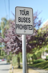 A sign reading 'Tour Buses Prohibited' stands against a blurred natural background.