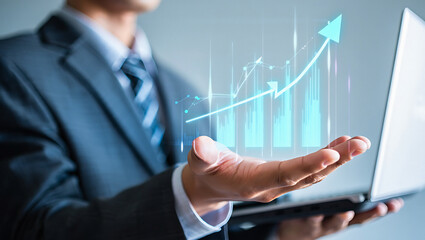 Businessman holding laptop with upward trending graph overlayed on hand showing growth concept