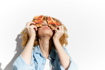 Woman holding pizza slices in front of her face, expressing joy and playfulness Bright background...