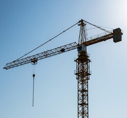 A towering construction crane against a clear blue sky, ready for work.