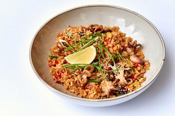A Vibrant Plate of Spicy Rice with Succulent Octopus, Fresh Vegetables, and a Zesty Lime Slice for an Invigorating Culinary Experience