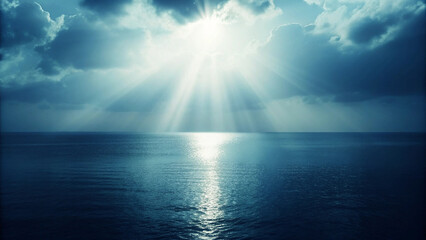 Sunbeams breaking through dramatic clouds over a calm ocean at sunset