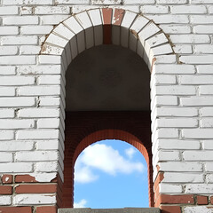 White brick wall with hole revealing blue sky and clouds