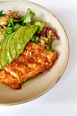 Crispy Fried Fish Fillet Served on a Bed of Fresh Mixed Greens Topped with Sliced Avocado Garnished with a Light Dressing