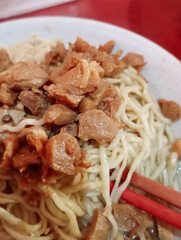 close-up of a bowl of indonesian chicken noodles,  featuring tender chicken pieces, savory broth, and chopsticks, ready to be enjoyed