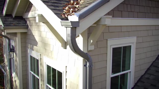 Exterior view of a house with gray gutters and a light beige siding
