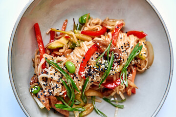 Delicious Stir-Fried Noodles with Colorful Vegetables and Savory Meat, Topped with Sesame Seeds for a Flavorful Asian Culinary Experience
