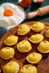 Freshly Made Dumplings Arranged Artistically on a Wooden Board Surrounded by Flour and Eggs, Perfect for Culinary Enthusiasts to Enjoy and Create Delicious Dishes.