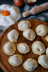 Freshly Made Dumplings Arranged Neatly on a Wooden Board Surrounded by Flour and Eggs, Showcasing a Traditional Culinary Craft