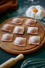 Delicious Homemade Ravioli Preparing Process with Fresh Ingredients Arranged on a Wooden Board Surrounded by Flour and an Egg Yolk