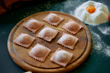 An Assortment of Freshly Made Ravioli Placed on a Rustic Wooden Board Surrounded by Flour and a Fresh Egg, Perfect for a Delicious Italian Meal
