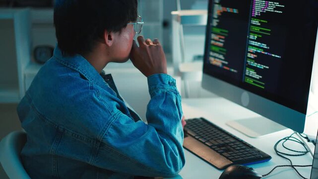 Software developer using keyboard focused on debugging programming code on dual monitor setup in tech environment