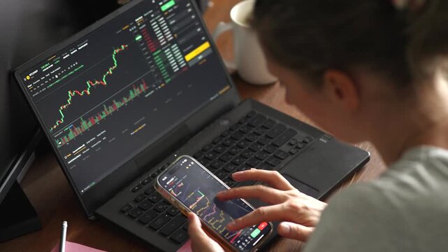 Financial Analyst Using Multiple Screens for Real-Time Data Monitoring 