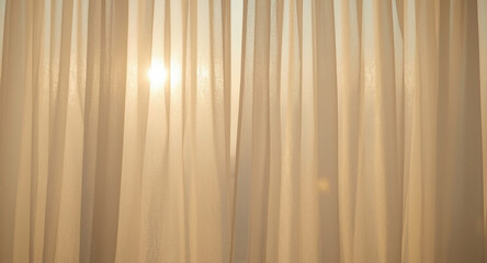 Obraz premium Sunlight streams through sheer, light-colored curtains, creating a soft, warm glow and highlighting the fabric's texture.