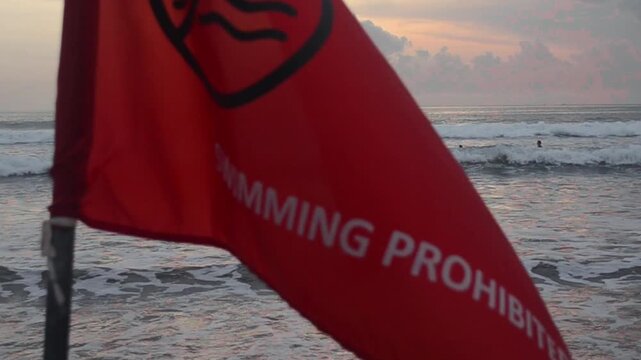 Swimmer Ignores "Swimming Prohibited" Flag at the Beach At Bali, Juli 2025 Kuta Beach &ndash;  Editorial Footage A swimmer ignores the warning and enters the sea.