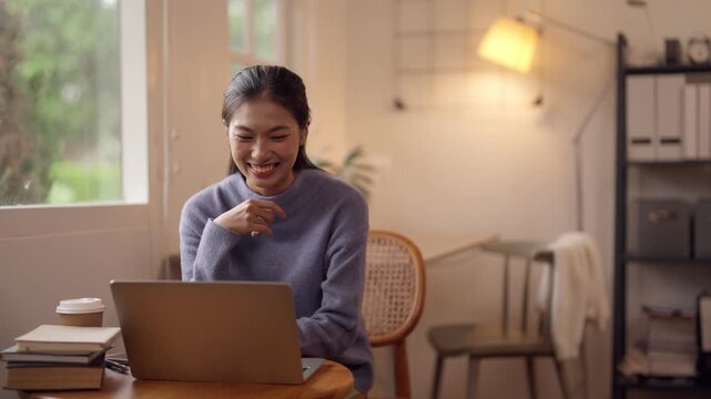 Asian woman remotely working from home using laptop computer for online tasks cozy comfortable home environment digital lifestyle learning