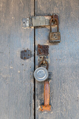 wooden door is secured with both a rusty metal hasp and a combination lock.