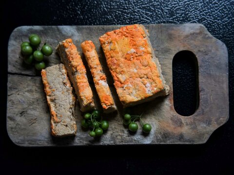Traditional Indonesian food called Oncon or fermented soybean cake on a cutting board with a black background.