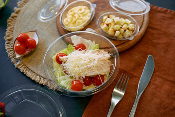 A Fresh Salad with Cherry Tomatoes, Shredded Cheese, and Crisp Lettuce Served on a Rustic Table Setting with Additional Sides in Containers