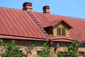 A traditional-style building with a bright red roof and two chimneys, suitable for use in rural or country-themed images