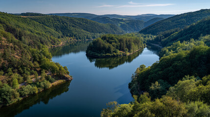Aerial view of a tranquil lake surrounded by lush green forests and rolling hillsides