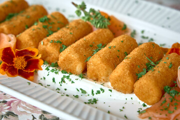 A Delicious Platter of Golden-Brown Croquettes Garnished with Fresh Herbs and Colorful Edible Flowers, Perfect for Entertaining Guests or Enjoying a Tasty Snack