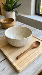 Minimalist Tabletop with Speckled Ceramic Bowl, Wooden Spoon, and Plant by Window