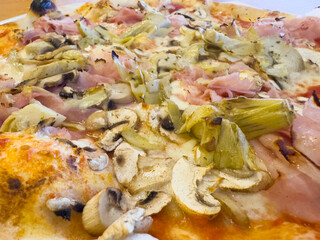 Delicious italian pizza with mushrooms, ham, artichokes, and cheese topping