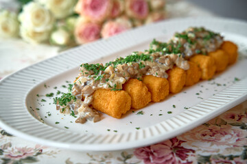 A Delicious Platter of Crispy Golden Nuggets Topped with Creamy Mushroom Sauce and Fresh Chopped Herbs Garnished for a Special Occasion.