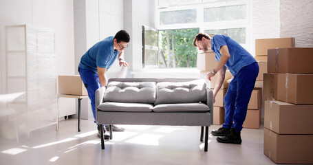 Hardworking Latino Movers Carefully Wrapping Sofas Inside Residential Homes