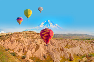 Hot air balloon flying over Cappadocia Erciyes mountain in the background - Goreme (Göreme),...