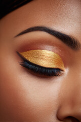 closed eye with golden eyeshadow and curled lashes