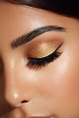 closed eye with golden eyeshadow and curled lashes