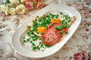A Beautifully Presented Plate of Eggs, Peas, and Ham on a Floral Tablecloth, Complemented by Soft Roses in the Background