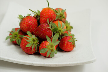 Delicious fresh and ripe strawberries in a white ceramic plate on a white background
