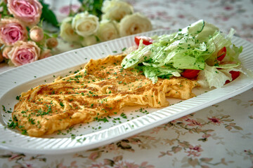 Deliciously Crafted Omelette Accompanied by a Fresh Salad on a Floral Tablecloth Perfect for Delighting the Senses and Enjoying a Culinary Experience