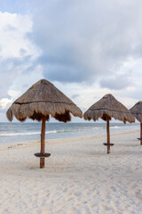 This serene beach scene features colorful palapa umbrellas on the sandy shore against a dramatic cloudy sky, embodying relaxation and making it perfect for vacationthemed imagery of summer leisure