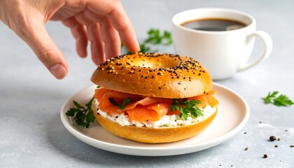 A hand reaches for a bagel with smoked salmon and cream cheese, accompanied by coffee