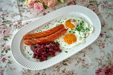 A Delicious Plate Featuring Grilled Sausages, Perfectly Cooked Eggs, and Savory Kidney Beans Garnished with Fresh Herbs on a Floral Tablecloth