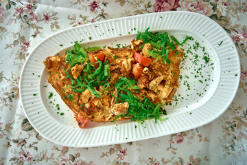 A Deliciously Prepared Omelette Garnished with Fresh Vegetables on a Decorative Plate Surrounded by Floral Tablecloth