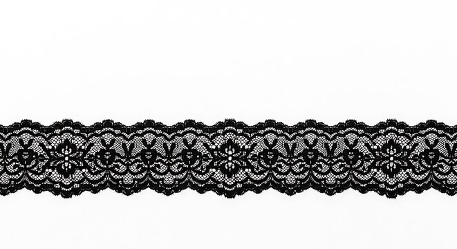 A close up shot of black lace trim with floral and scalloped edge on a white background surface